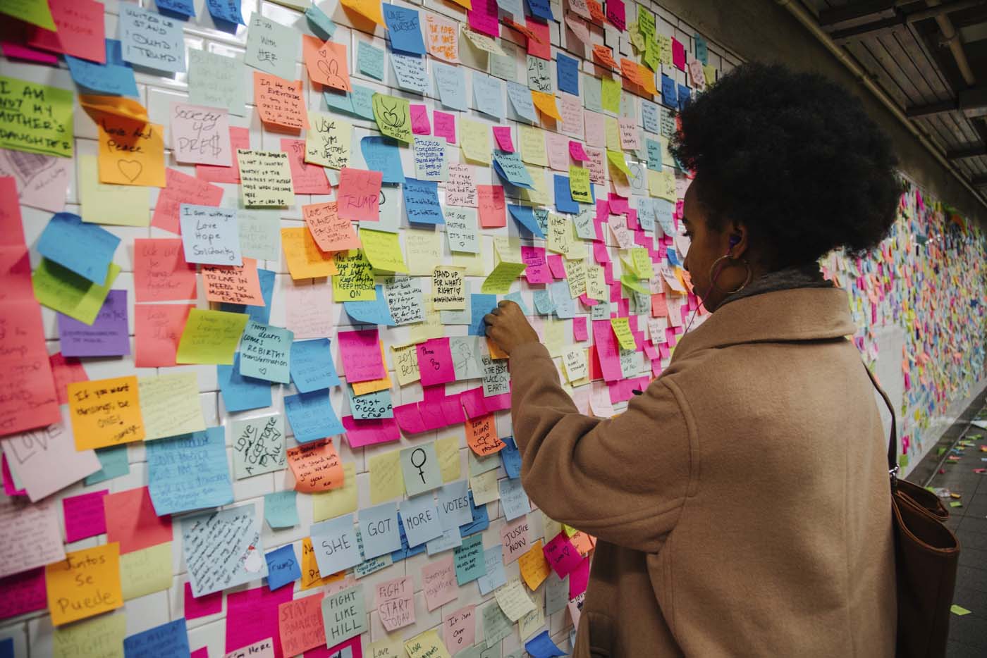 AVX9 NUEVA YORK (ESTADOS UNIDOS) 13/11/2016.- Una ciudadana pega una nota para participar en la pieza artística "Subway Therapy" en uno de los muros de la estación de metro de Union Square en Manhattan, Nueva York (Estados Unidos) hoy, 13 de noviembre de 2016. El número de post-it de la obra, que inició el artista estadounidense Matthew Chavez el 10 de noviembre, continúa creciendo mientras los ciudadanos siguen añadiendo nuevas notas. EFE/Alba Vigaray