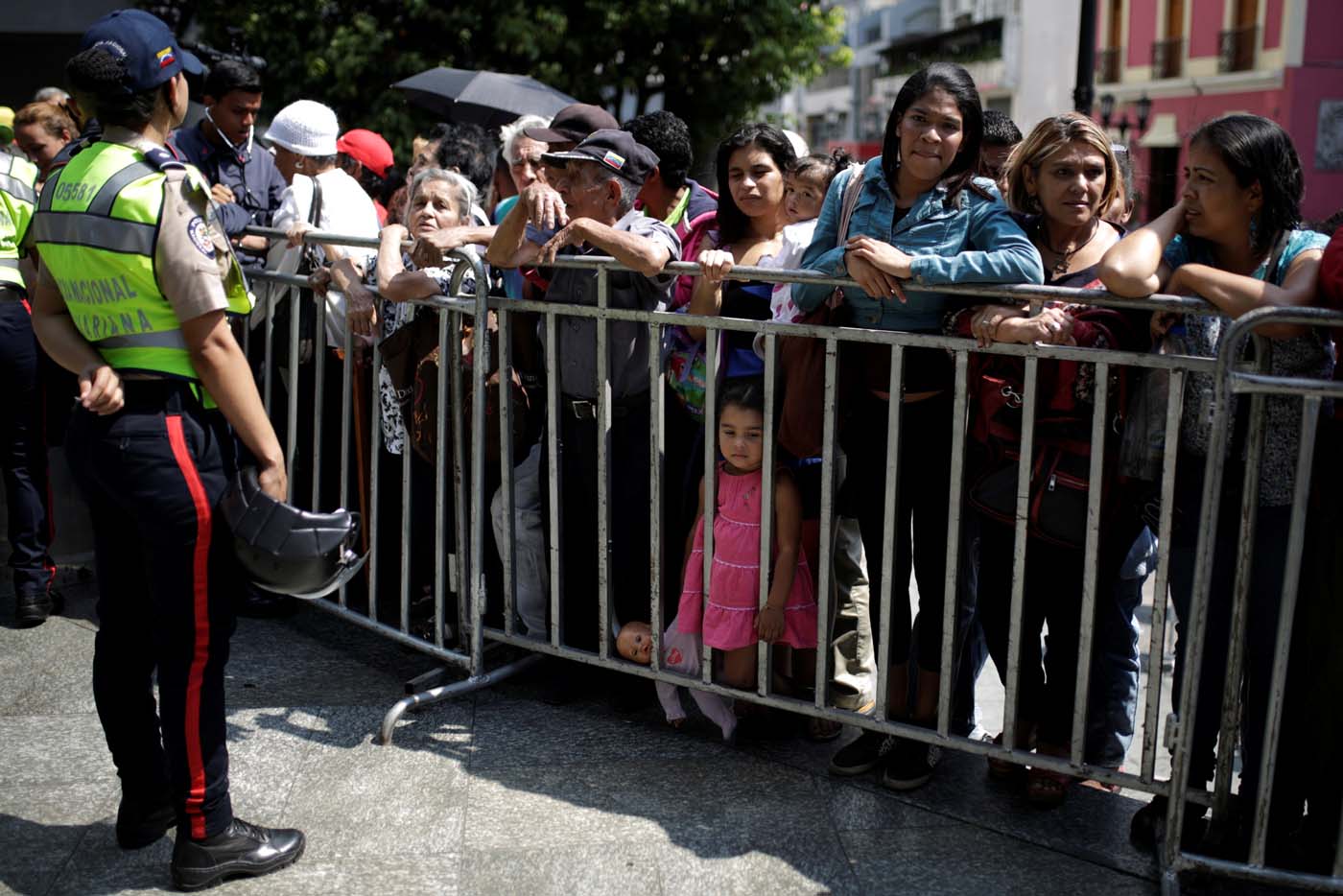 People wait to apply for a card that will register them for government social programmes, in front of a police officer, in Caracas, Venezuela January 20, 2017. REUTERS/Marco Bello