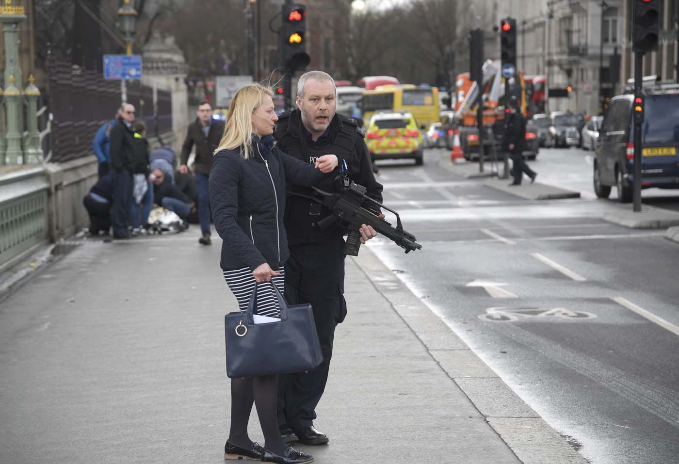 An armed police officer assists a woman after an incident on Westminster Bridge in London, March 22, 2017. REUTERS/Toby Melville