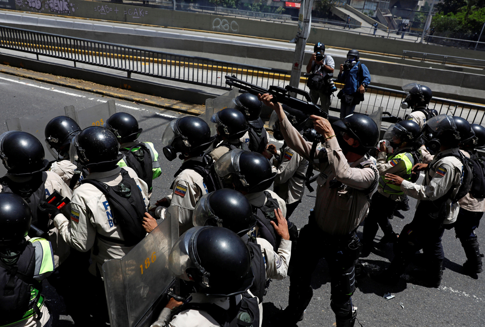 A riot police officer holds a weapon in the direction of demonstrators during an opposition rally in Caracas, Venezuela, April 8, 2017. REUTERS/Carlos Garcia Rawlins