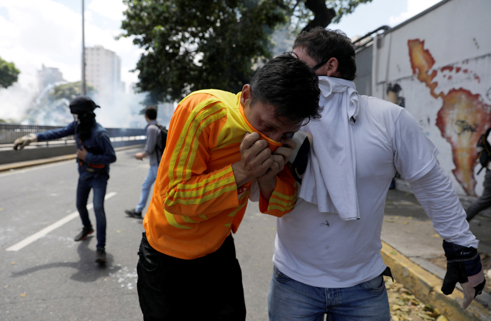 Demonstrators take cover as the riot police clashes with opposition suporters during a rally in Caracas, Venezuela, April 8, 2017. REUTERS/Carlos Garcia Rawlins