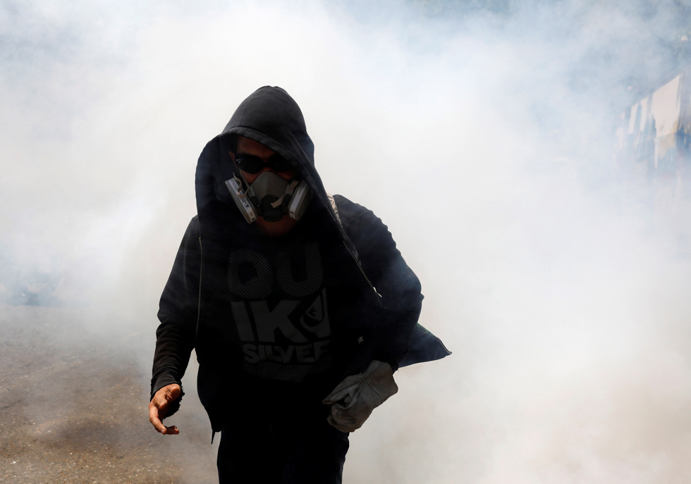 A demonstrator walks away from tear gas as riot police clashes with opposition suporters during a rally in Caracas, Venezuela, April 8, 2017. REUTERS/Carlos Garcia Rawlins