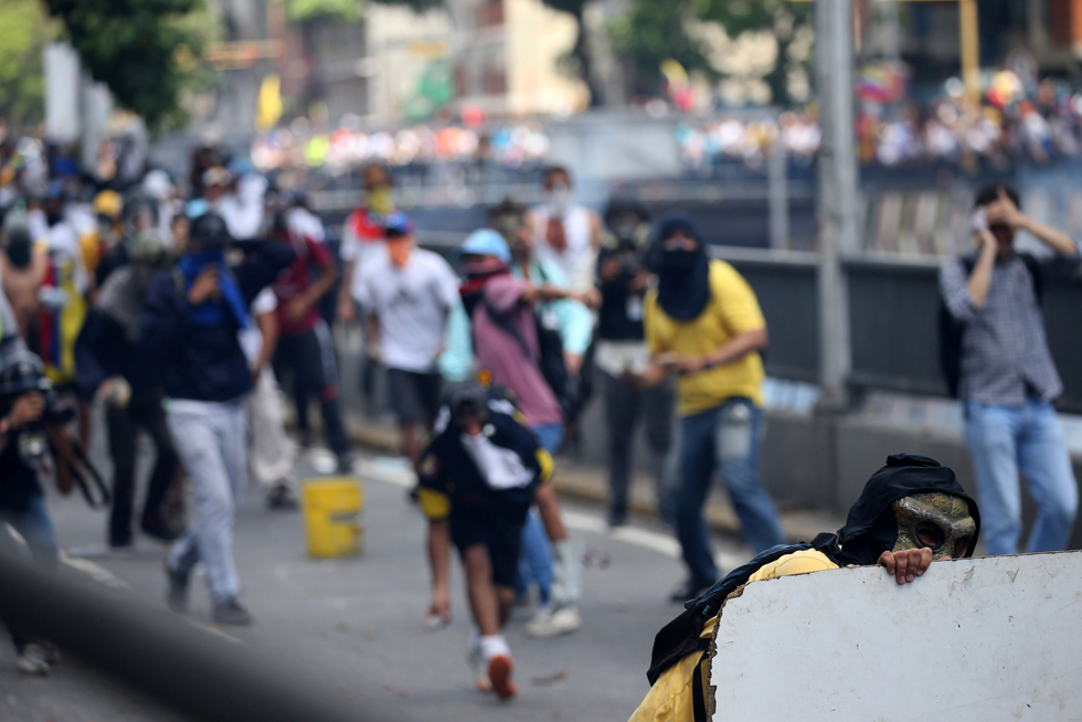 A demonstrator looks from behind a barricade during clashes with the riot police during a rally in Caracas, Venezuela, April 8, 2017. REUTERS/Carlos Garcia Rawlins