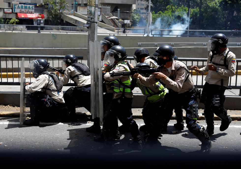 Riot police officers take cover during clashes with demonstrators at a rally in Caracas, Venezuela, April 8, 2017. REUTERS/Carlos Garcia Rawlins