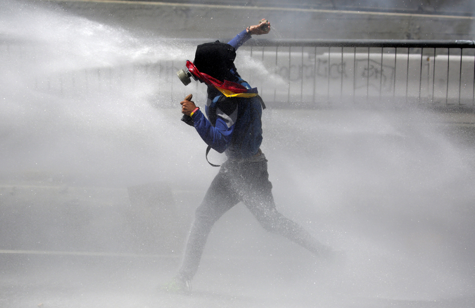 A demonstrator gets hit with a water canon while clashing with riot police during a rally in Caracas, Venezuela, April 8, 2017. REUTERS/Marco Bello