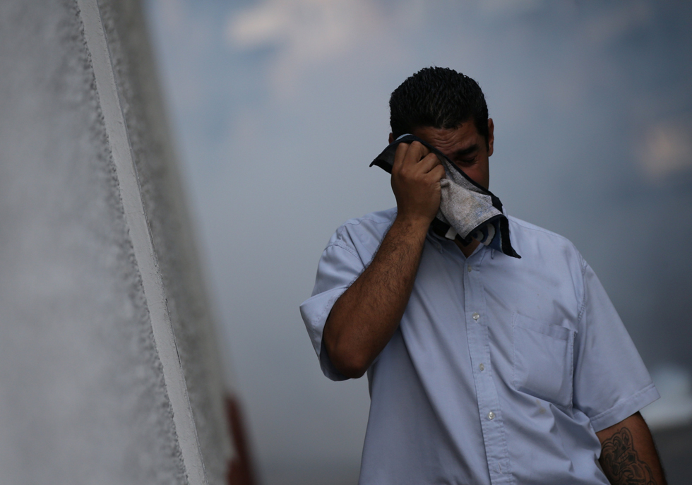 A pedestrian covers his face with a handkerchief to avoid the tear gas as demonstrators clashes with riot police during a rally in Caracas, Venezuela, April 8, 2017. REUTERS/Carlos Garcia Rawlins