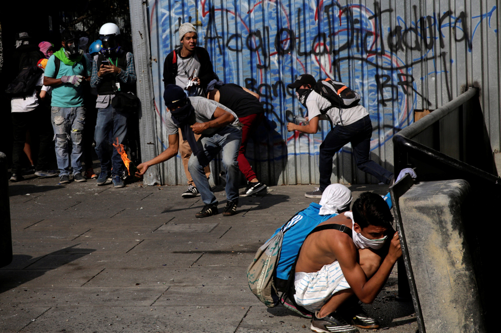 Demonstrators barricade the front of an office of the Supreme Court of Justice as another throws a petrol bomb during a rally in Caracas, Venezuela, April 8, 2017. REUTERS/Marco Bello