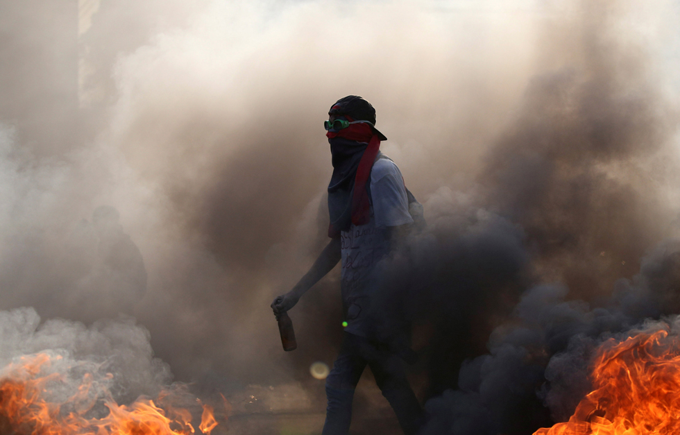 A demonstrator walks while building a fire on the street during a rally in Caracas, Venezuela, April 8, 2017. REUTERS/Carlos Garcia Rawlins