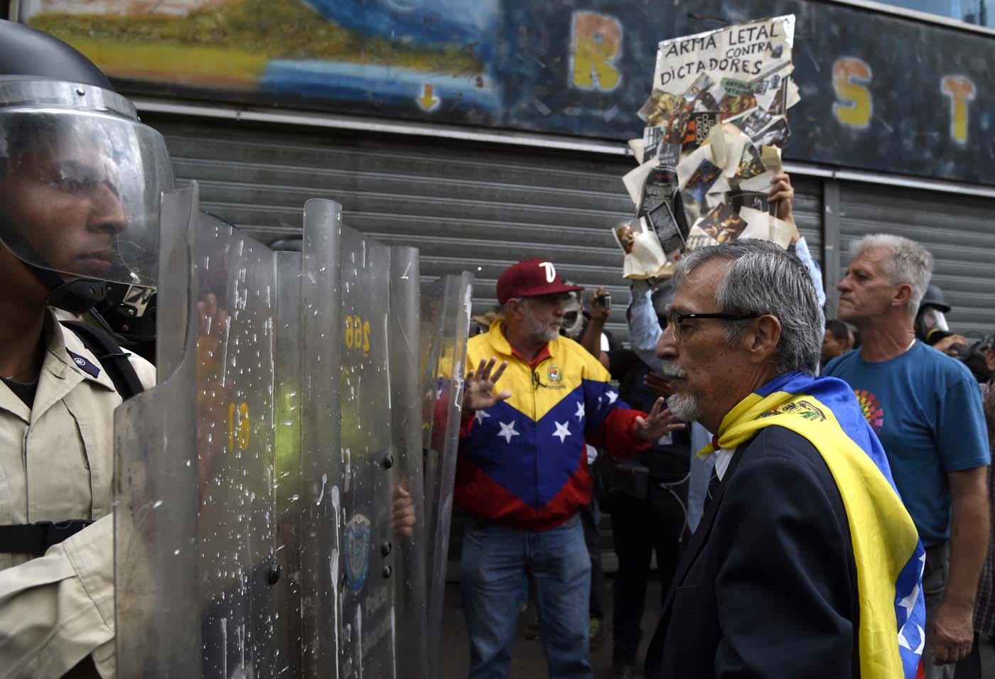 Opposition activists confront riot police during a protest against the government in Caracas on May 12, 2017. Daily clashes between demonstrators -who blame elected President Nicolas Maduro for an economic crisis that has caused food shortage- and security forces have left 38 people dead since April 1. Protesters demand early elections, accusing Maduro of repressing protesters and trying to install a dictatorship. / AFP PHOTO / JUAN BARRETO