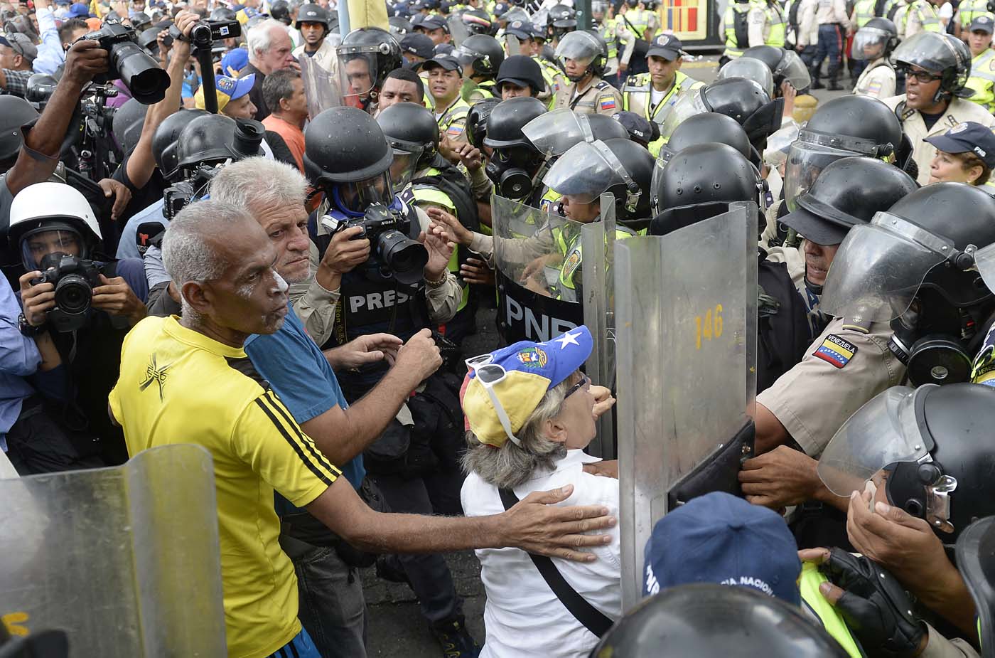 Opposition activists confront riot police during a protest against the government in Caracas on May 12, 2017. Daily clashes between demonstrators -who blame elected President Nicolas Maduro for an economic crisis that has caused food shortage- and security forces have left 38 people dead since April 1. Protesters demand early elections, accusing Maduro of repressing protesters and trying to install a dictatorship. / AFP PHOTO / FEDERICO PARRA