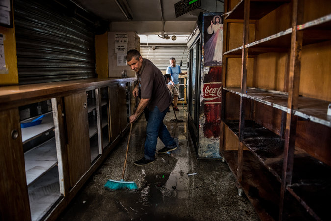 Los trabajadores de un supermercado de Caracas limpian el local después de un saqueo, en abril. Credit Meridith Kohut para The New York Times