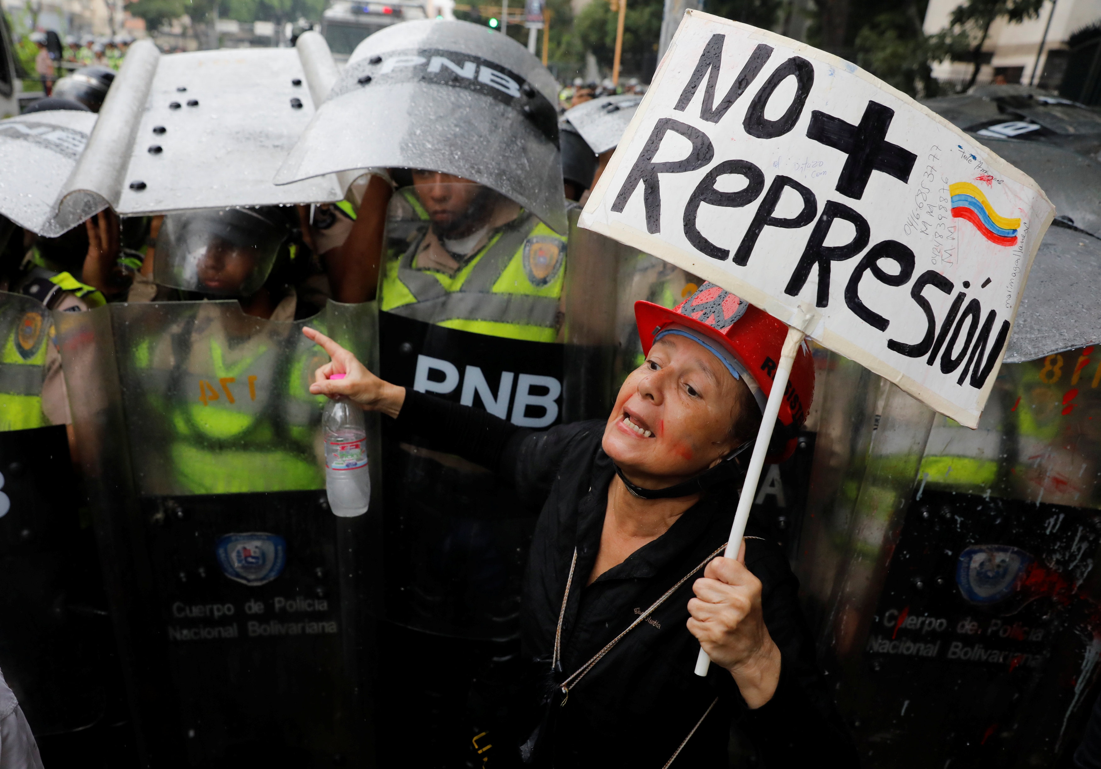 An opposition supporter confronts riot security forces with a sign that reads "No more repression" during a rally against President Nicolas Maduro in Caracas, Venezuela, May 12, 2017. REUTERS/Carlos Garcia Rawlins