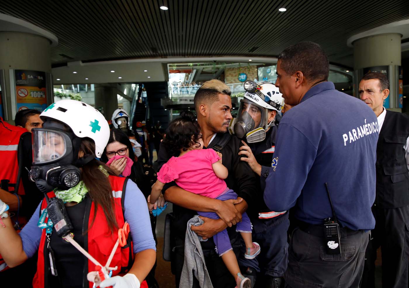 A man carries a child out of a shopping mall when smoke from tear gas fired by security forces got inside of it as clashes occured during a rally against Venezuelan President Nicolas Maduro's government in Caracas, Venezuela, July 6, 2017. REUTERS/Carlos Garcia Rawlins