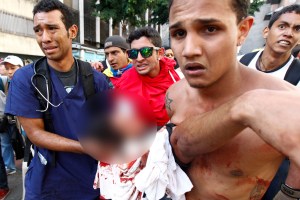 A dead protester is carried away on a motorcycle after gun shots were heard during an anti-government rally in Caracas