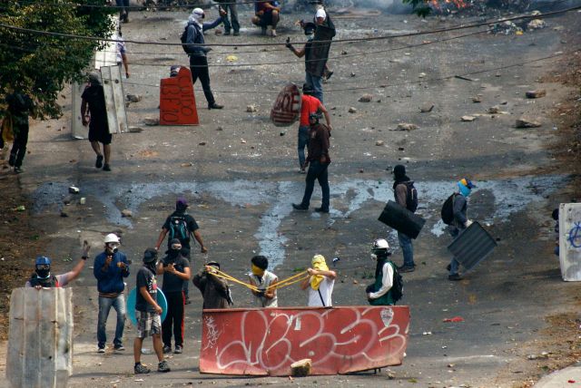 Anti-government protesters use a slingshot during a protest in San Cristobal