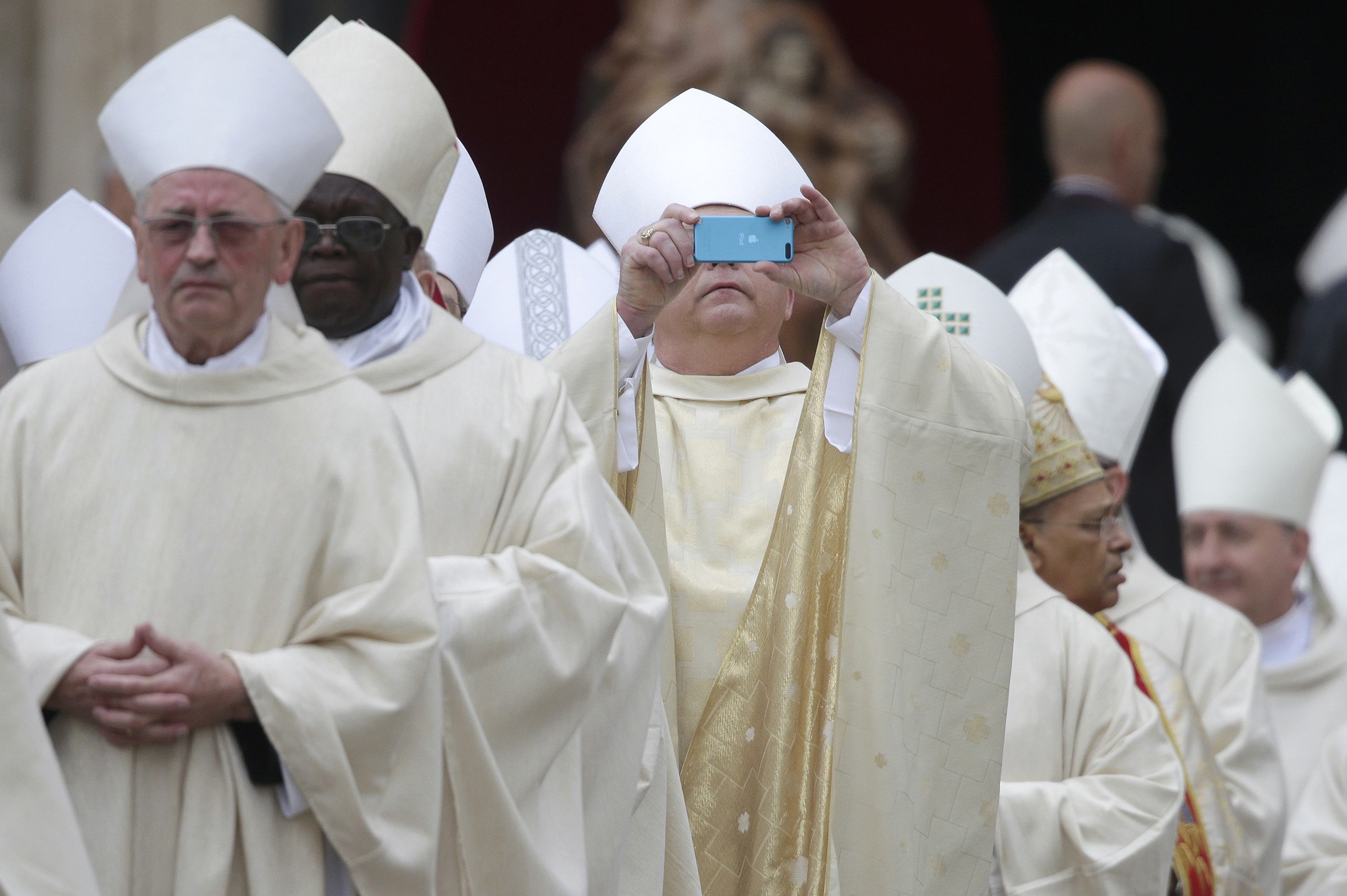 A bishop uses his mobile phone to take photographs as he arrives for ...