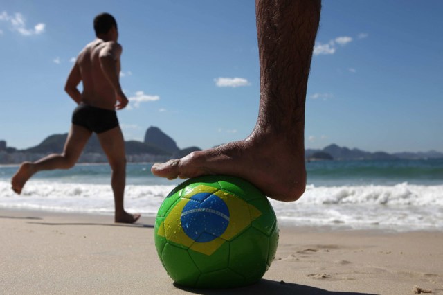 Foto: Detalle de un balón de fútbol con la bandera de Brasil en la playa carioca de Copacabana, donde una enorme sala de prensa ya se eleva sobre la avenida Atlántica, hoy lunes 12 de mayo de 2014, a la espera de la llegada de los reporteros que hablarán de fútbol, con el cerro Pan de Azúcar de telón de fondo, cuando falta un mes exacto para que ruede el balón en el partido inaugural del Mundial Brasil 2014. Brasil tiene muchas obras pendientes, tanto en estadios de fútbol como en aeropuertos o redes de telefonía. EFE/ Marcelo Sayão