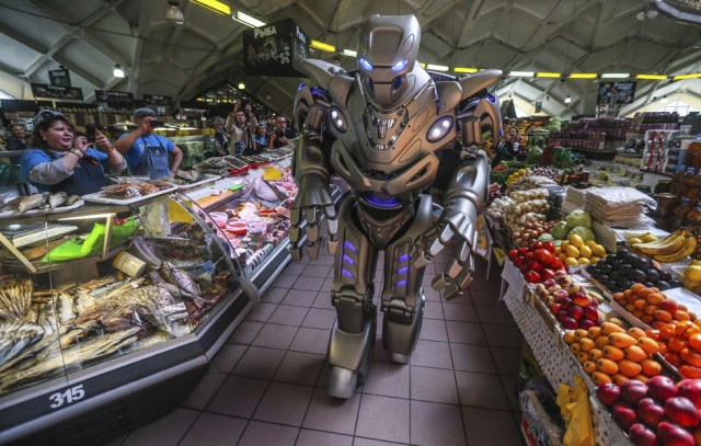 Foto: Varios empleados de un puesto de comida toman fotografías de "Titan", un robot creado por la compañía del Reino Unido England Cyberstein Robots y que ha trabajado junto a Rihanna, Will Smith, o Jackie Chan, durante su visita al mercado de Danilovsly en el centro de Moscú (Rusia) hoy, lunes 12 de mayo del 2014. "Titan" ha visitado Moscú para acudir a Bal Rotov, una exposición interactiva de los avances más recientes en robótica que se celebrará el próximo día 15 de mayo en el centro de exposiciones Artplay Moscú. EFE/Sergei Ilnitsky