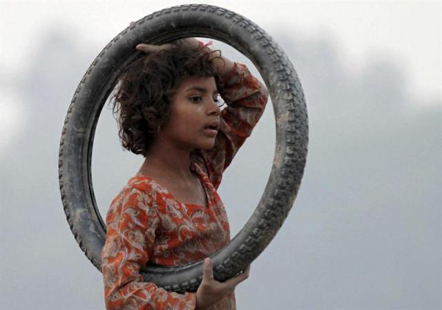 Un niño juega con un neumático en Lahore (Pakistán) hoy, miércoles 19 de noviembre de 2014, en víspera de la celebración del Día Mundial de la Infancia. EFE/Rahat Dar 