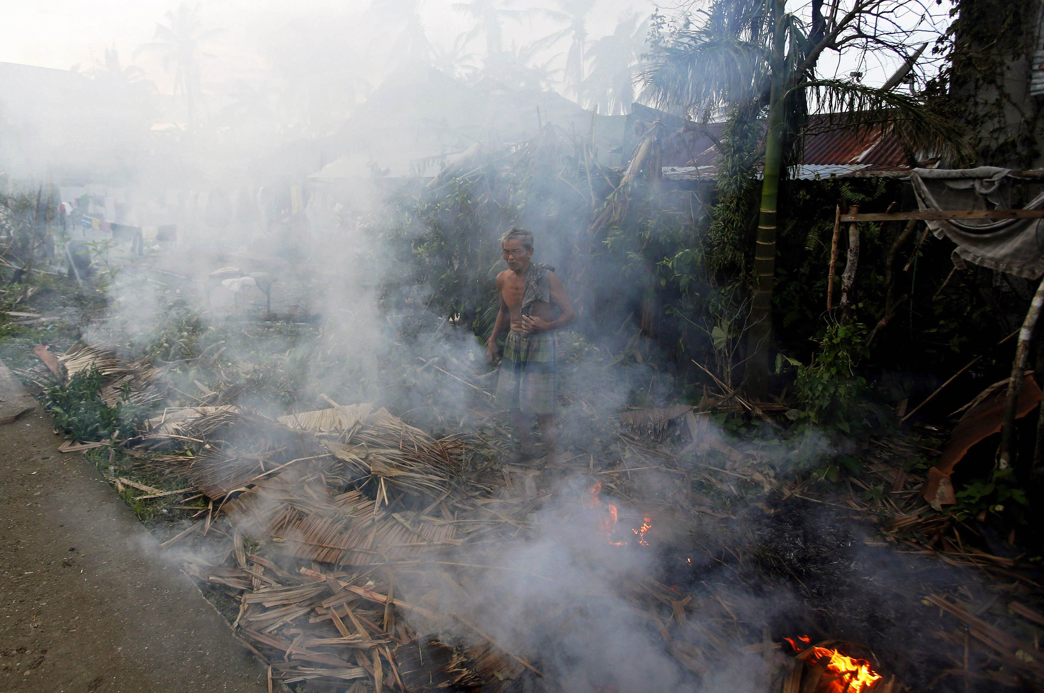 A resident burns debris brought at the height of Typhoon Hagupit in ...