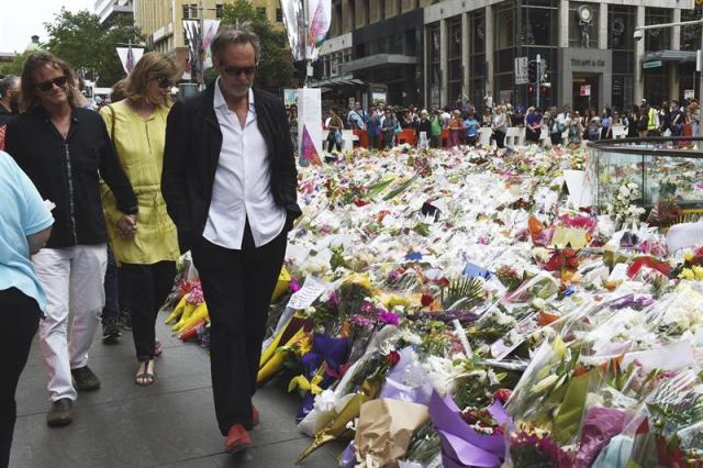 Familiares de Tori Johnson y Katrina Dawson, que fallecieron en el secuestro ocurrido en el "Lindt Chocolate Cafe", visitan Martin Place, en Sídney, hoy 17 de diciembre de 2014, donde cientos de ramos de flores llenan la plaza en homenaje a las víctimas. El pasado lunes 15 el clérigo iraní Man Haron Monis secuestró una cafetería en Sídney con 17 personas dentro que, tras la intervención policial, concluyó con la muerte del secuestrador y dos rehenes. EPA/DEAN LEWIN