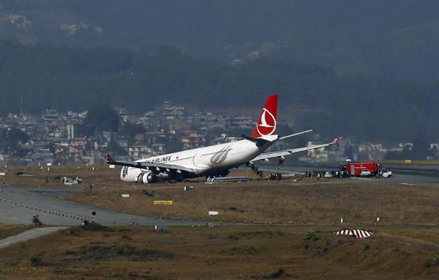 Miembros de los servicios de emergencia inspeccionan un airbus de Turkish Airlines después de que se saliera de la pista al aterrizar en el aeropuerto internacional de Katmandú (Nepal) hoy, miércoles 4 de marzo de 2015. Cuatro pasajeros han resultado heridos al salirse de la pista el avión en el que viajaban cuando este realizaba un aterrizaje brusco. El avión, que ya había intentado aterrizar una vez sin éxito, consiguió tomar tierra casi una hora después en un segundo intento pero una de sus ruedas aterrizó fuera de pista, lo que ocasionó un pinchazo y que el avión se saliera de la pista de aterrizaje. EFE/Narendra Shrestha