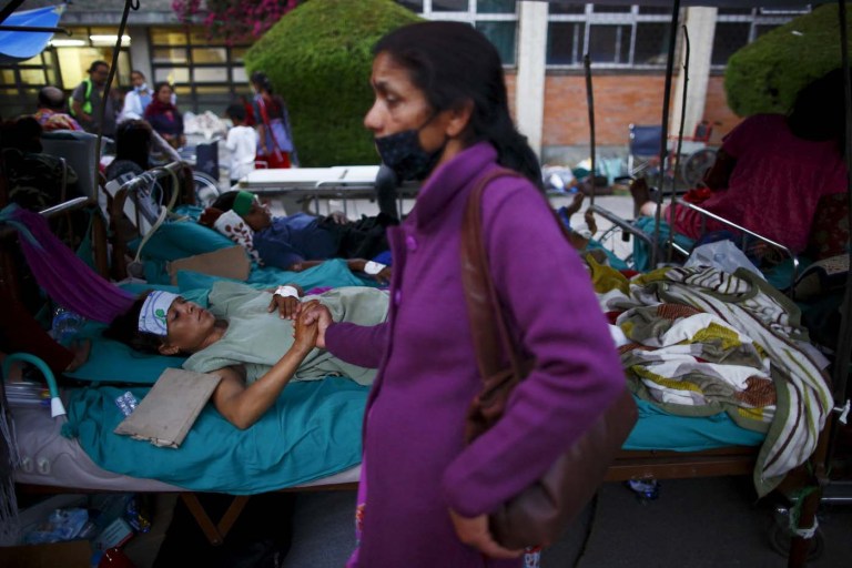 A family member holds the hand of an earthquake victim after being ...