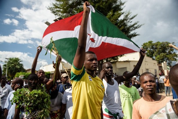 Foto: Los hombres ocupan la bandera de un Burundi personas salen a las calles a celebrar, agitando ramas, sonar bocinas de los coches y desfilando por Bujumbura el 13 de mayo 2015, tras el anuncio de radio por el general Godefroid Niyombare que el presidente Nkurunziza fue derrocado. / AFP