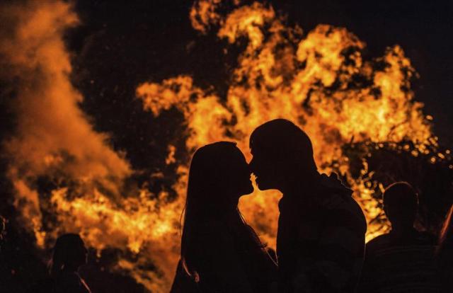 Una pareja se besa junto a la hoguera de solsticio de verano en Friburgo (Alemania) ayer, domingo 21 de junio de 2015. La hoguera se celebra cada año para conmemorar el día más largo y la noche más corta del año. EFE/Patrick Seeger