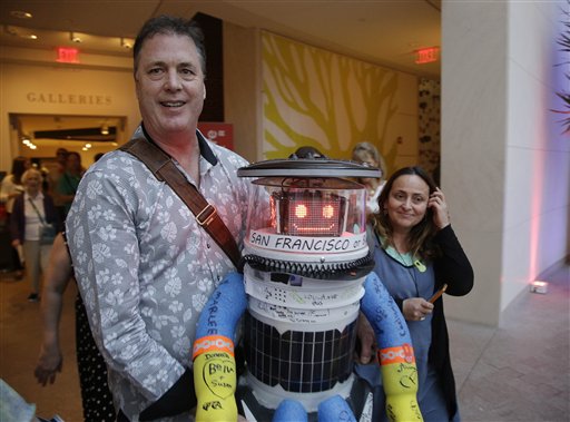 Foto: El co-creador David Harris Smith carga al hitchBOT, un robot que viaja de dedo, cuando lo introduce a una audiencia en Estados Unidos en el museo Peabody Essex el 16 de julio de 2015 en Salem, Massachusetts. HitchBOT comenzará su viaje costa a costa de Estados Unidos, después de concluir aventuras similares en Canadá y Europa. Los planes para hitchBOT son salir del área de Boston el viernes con el destino final en mente de San Francisco (Foto AP/Stephan Savoia)