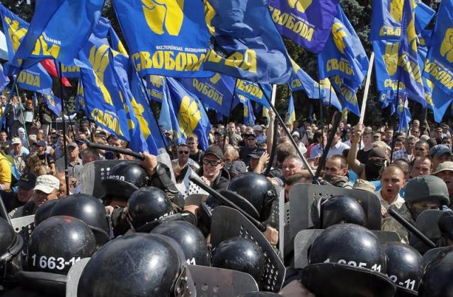 Opositores de la reforma constitucional se enfrentan a la policía ante el Parlamento ucraniano en Kiev (Ucrania) hoy, 31 de agosto de 2015. Una veintena de militares y una decena de policías resultaron heridos hoy a consecuencia de una explosión junto a la sede del Parlamento de Ucrania durante enfrentamientos entre las fuerza de seguridad y un grupo de manifestantes radicales, informaron las autoridades. Los radicales, según medios locales, lanzaron un artefacto explosivo contra el cordón policial que custodiaba el Parlamento poco después de que el Legislativo aprobara una reforma constitucional para descentralizar el país. EFE/Sergey Dolzhenko