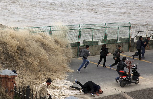 Un visitante cae, ya que huyen de una ola causada por una marejada que subió más allá de una barrera en las orillas del río Qiantang, en Hangzhou, provincia de Zhejiang, China, 28 de octubre de 2015. REUTERS / China Daily CHINA OUT. NO VENTAS COMERCIALES O EDITORIALES EN CHINA