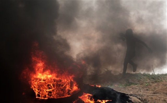 Un palestino corre para protegerse durante choques con soldados israelíes en la frontera de Gaza con Israel el viernes, 6 de noviembre del 2015.   (Foto AP/ Khalil Hamra)