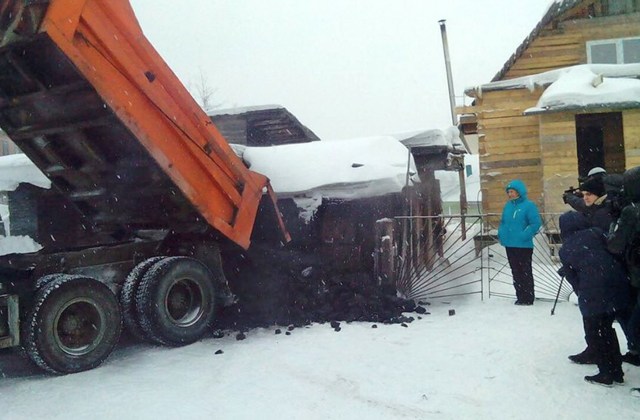 En esta imagen tomada el miércoles 23 de diciembre de 2015, Yelena Salnikova, con una chaqueta azul, enfermera de la pequeña localidad de Berezovskiy, Rusia, recibe un camión lleno de carbón de las autoridades en la región carbonífera de Kemerovo por haber adelgazado 30 kilos (66 libras), en Siberia, Rusa. (Anton Gorelkin/Servicio de prensa de de la Administración Regional de Kemerovo via AP)