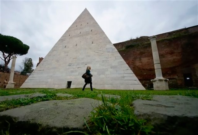 Una mujer camina frente a la Pirámide Cestia en Roma el miércoles 3 de febrero de 2016. La única pirámide sobreviviente de la antigüedad en Roma obtendrá nueva cara. Después de que un magnate de la industria textil japonés pagara la limpieza, los arqueólogos están ansiosos por presumir el monumento, construido hace unos 2.000 años como una tumba para enterrar al pretor romano, o magistrado, llamado Cayo Cestio.  (Foto AP/Domenico Stinellis)