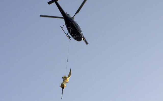 A helicopter lifts the statue of the Archangel Michael from the top of Mont Saint-Michel Abbey on March 15, 2016.  The Centre for National Monuments (CMN) removed the statue which also acts as a lightning rod as part of the project to restore the lightning rod device.  / AFP / DAMIEN MEYER