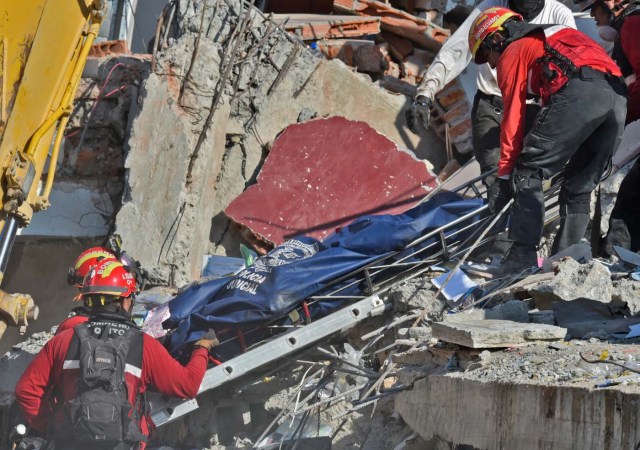 Rescuers remove a corpse from the rubble in Manta, Ecuador on April 19, 2016, two days after the 7.8-magnitude quake that struck the region. Rescuers and desperate families clawed through the rubble Monday to pull out survivors of an earthquake that killed at least 413 people and destroyed towns in a tourist region of Ecuador. / AFP PHOTO / LUIS ACOSTA