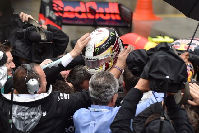 Mercedes AMG Petronas F1 Team's British driver Lewis Hamilton (C) is congratulated by teammates and fans after winning the Brazilian Grand Prix at the Interlagos circuit in Sao Paulo, Brazil, on November 13, 2016. / AFP PHOTO / Miguel SCHINCARIOL