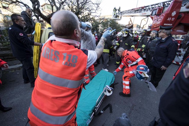 ITA01 ROMA (ITALIA), 28/12/2016.- Varios bomberos preparan una camilla para auxiliar a la personas encontradas entre los escombros de un edificio colapsado en Acilia, Italia, hoy 28 de diciembre de 2016. Al menos dos personas fueron rescatadas de un edificio hundido tras una fuga de gas. EFE/Massimo Percossi