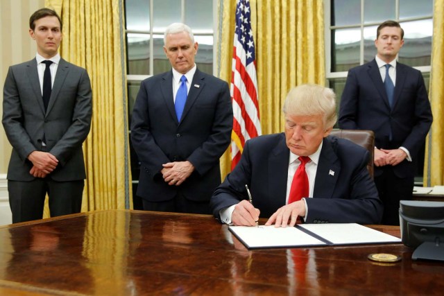 U.S. President Donald Trump, flanked by Senior Advisor Jared Kushner (standing, L-R), Vice President Mike Pence and Staff Secretary Rob Porter welcomes reporters into the Oval Office for him to sign his first executive orders at the White House in Washington, U.S. January 20, 2017. REUTERS/Jonathan Ernst TPX IMAGES OF THE DAY