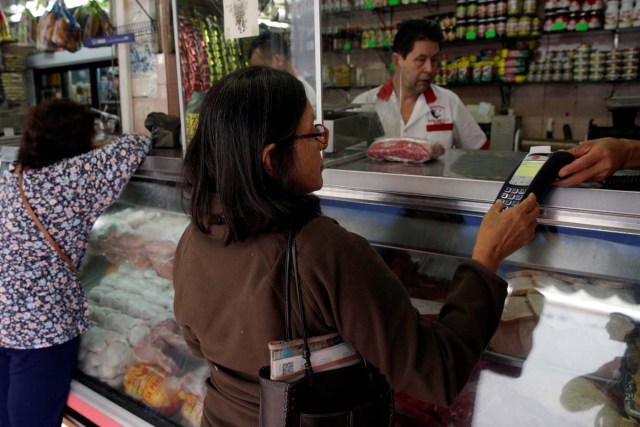 A woman uses a PoS device to pay for her groceries at a store in downtown Caracas, Venezuela March 10, 2017. REUTERS/Marco Bello