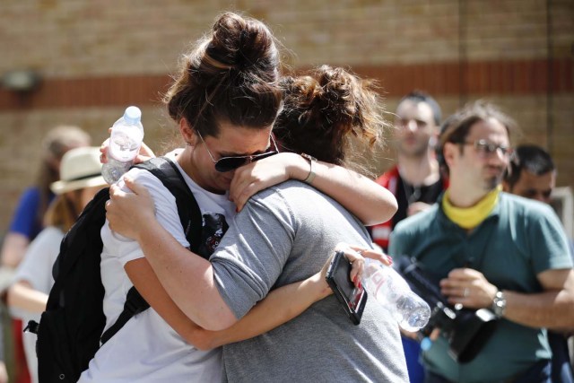 Two women embrace in the vicinity of the destroyed Grenfell Tower, a residential tower block in west London on June 15, 2017. Firefighters searched for bodies today in a London tower block gutted by a blaze that has already left 12 dead, as questions grew over whether a recent refurbishment contributed to the fire. / AFP PHOTO / Tolga AKMEN