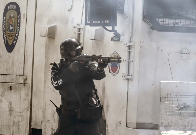 A policeman in riot gear takes aim in a clash with opposition activists during an anti-government protest in Caracas, on June 22, 2017. / AFP PHOTO / JUAN BARRETO