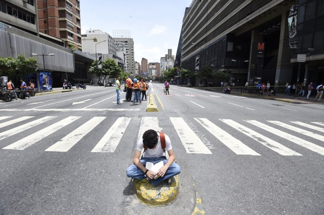 A Venezuelan opposition activist reads a book during a protest in Caracas on July 10, 2017. Venezuela hit its 100th day of anti-government protests Sunday, amid uncertainty over whether the release from prison a day earlier of prominent political prisoner Leopoldo Lopez might open the way to negotiations to defuse the profound crisis gripping the country. / AFP PHOTO / JUAN BARRETO