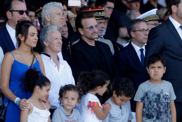 Singer of U2 Bono (C) looks on as he attends a ceremony in Nice, southern France on July 14, 2017, during a one year anniversary commemerations since a jihadist massacre in the Mediterranean city where a man drove a truck into a crowd, killing 86 people.  / AFP PHOTO / POOL / Laurent Cipriani
