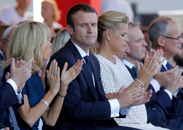 French President Emmanuel Macron (C) looks towards his wife Brigitte Macron during a ceremony in Nice, southern France on July 14, 2017, part of one year anniversary commemerations since a jihadist massacre in the Mediterranean city where a man drove a truck into a crowd, killing 86 people.  / AFP PHOTO / POOL / Laurent Cipriani