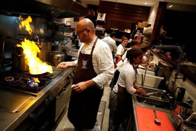 Chef Carlos Garcia (L) cooks within the kitchen of the Alto restaurant in Caracas, Venezuela June 29, 2017. Picture taken June 29, 2017. REUTERS/Ivan Alvarado