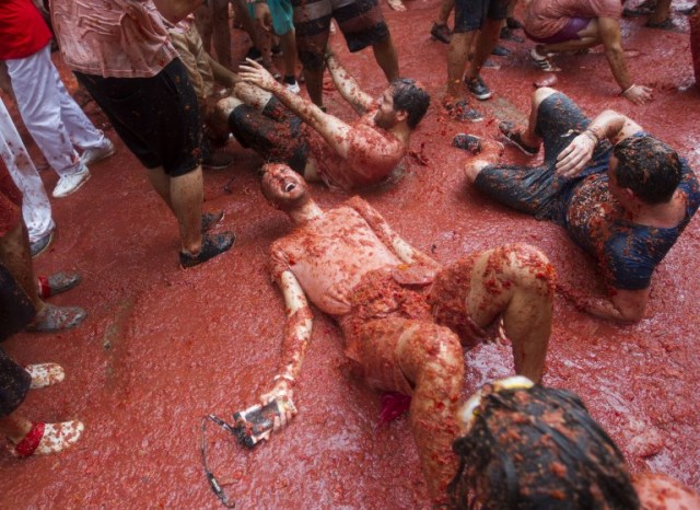 Revellers covered in tomato pulp take part in the annual "Tomatina" festival in the eastern town of Bunol, on August 30, 2017. The iconic fiesta -- which celebrates its 72nd anniversary and is billed at "the world's biggest food fight" -- has become a major draw for foreigners, in particular from Britain, Japan and the United States. / AFP PHOTO / JAIME REINA