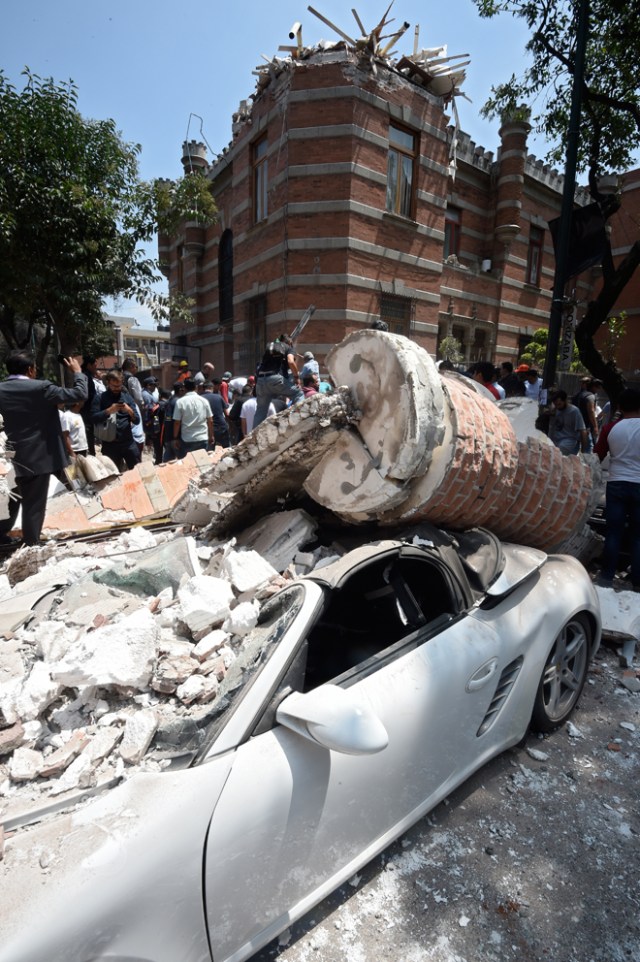 Picture of a car crashed by debris from a damaged building after a quake rattled Mexico City on September 19, 2017. A powerful earthquake shook Mexico City on Tuesday, causing panic among the megalopolis' 20 million inhabitants on the 32nd anniversary of a devastating 1985 quake. The US Geological Survey put the quake's magnitude at 7.1 while Mexico's Seismological Institute said it measured 6.8 on its scale. The institute said the quake's epicenter was seven kilometers west of Chiautla de Tapia, in the neighboring state of Puebla. / AFP PHOTO / Alfredo ESTRELLA