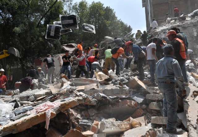 People remove debris of a collapsed building looking for possible victims after a quake rattled Mexico City on September 19, 2017. A powerful earthquake shook Mexico City on Tuesday, causing panic among the megalopolis' 20 million inhabitants on the 32nd anniversary of a devastating 1985 quake. The US Geological Survey put the quake's magnitude at 7.1 while Mexico's Seismological Institute said it measured 6.8 on its scale. The institute said the quake's epicenter was seven kilometers west of Chiautla de Tapia, in the neighboring state of Puebla. / AFP PHOTO / Omar TORRES